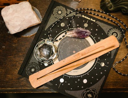 Mapa astral, incenso e cristais em cima de uma mesa de madeira.