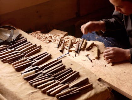 Un artesano creando una escultura decorativa en un negocio de artesanías en madera.