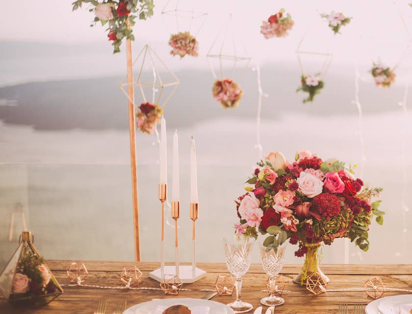 Una mesa de banquete decorada con flores y vajilla blanca con dorado en un negocio de planificación de bodas.