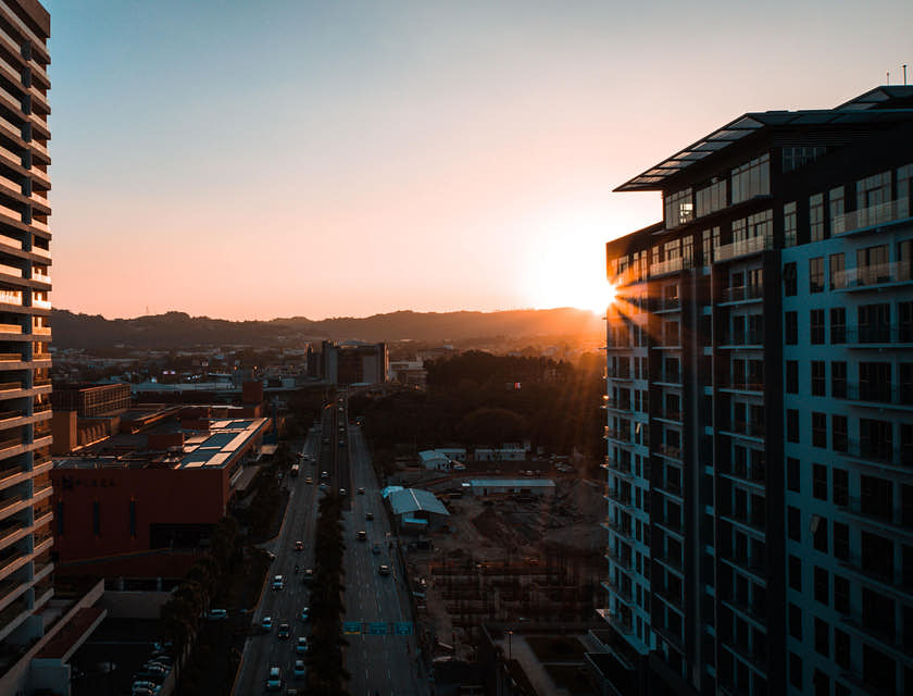 Edificios y una gran avenida con las montañas y el sol naciente de fondo en El Salvador.