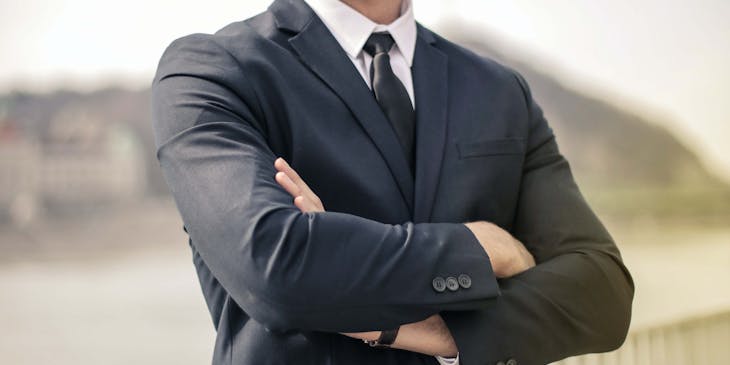 A confident man with crossed arms looking into the distance.