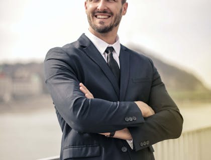 Un uomo dall’aspetto sicuro che guarda in lontananza con le braccia incrociate.