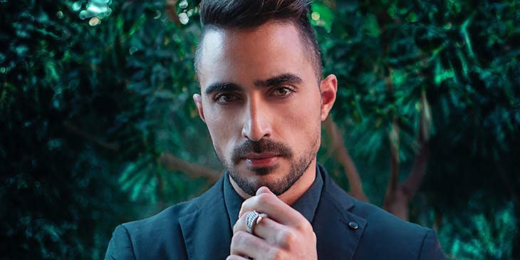 A dashing, debonair man wearing a suit with a silver watch and ring.