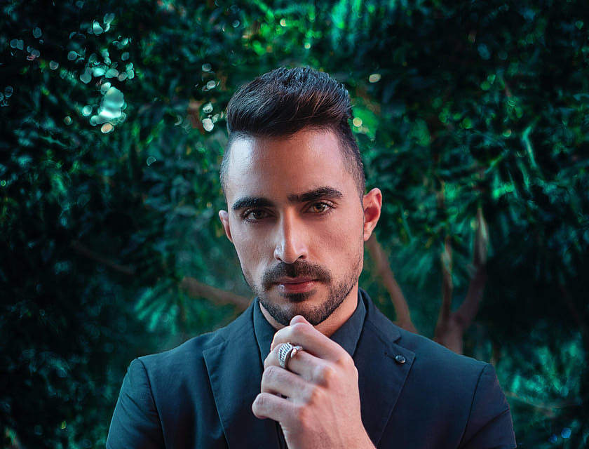 A dashing, debonair man wearing a suit with a silver watch and ring.