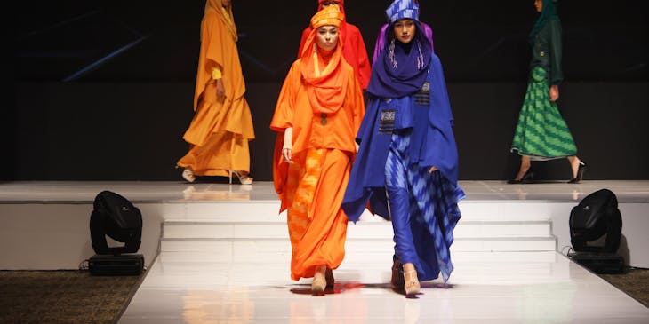 Models show off designer modest clothing on a runway.