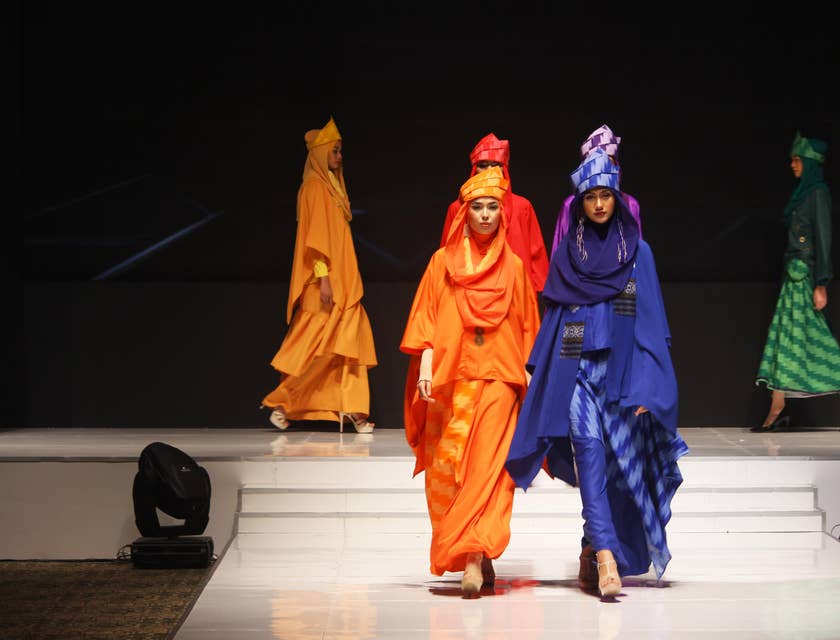 Models show off designer modest clothing on a runway.