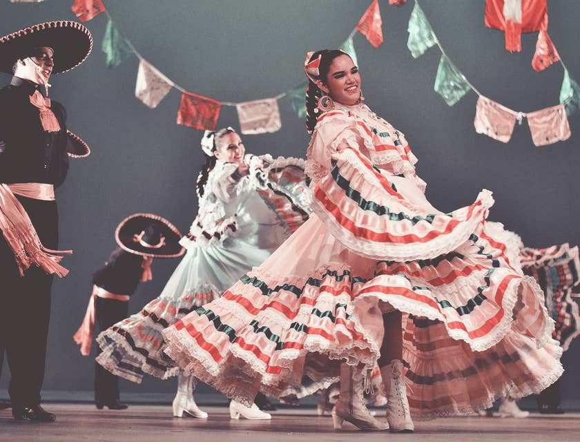 Hombres y mujeres vestidos con trajes típicos mexicanos bailando en una academia de danza folklórica.