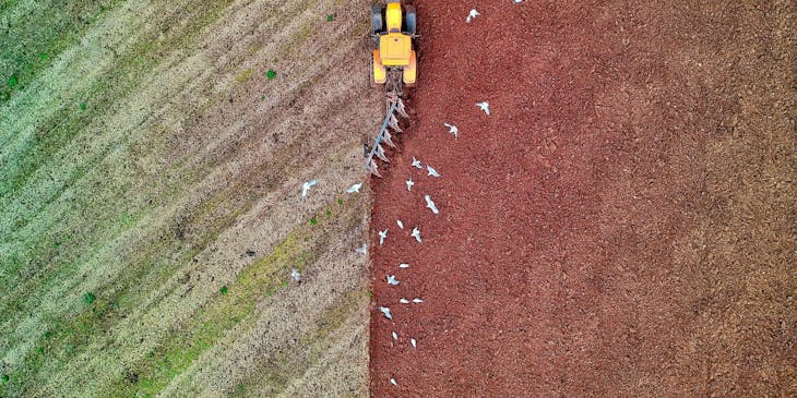 Vista aérea de un tractor agrícola trabajando la tierra en una asociación agropecuaria.