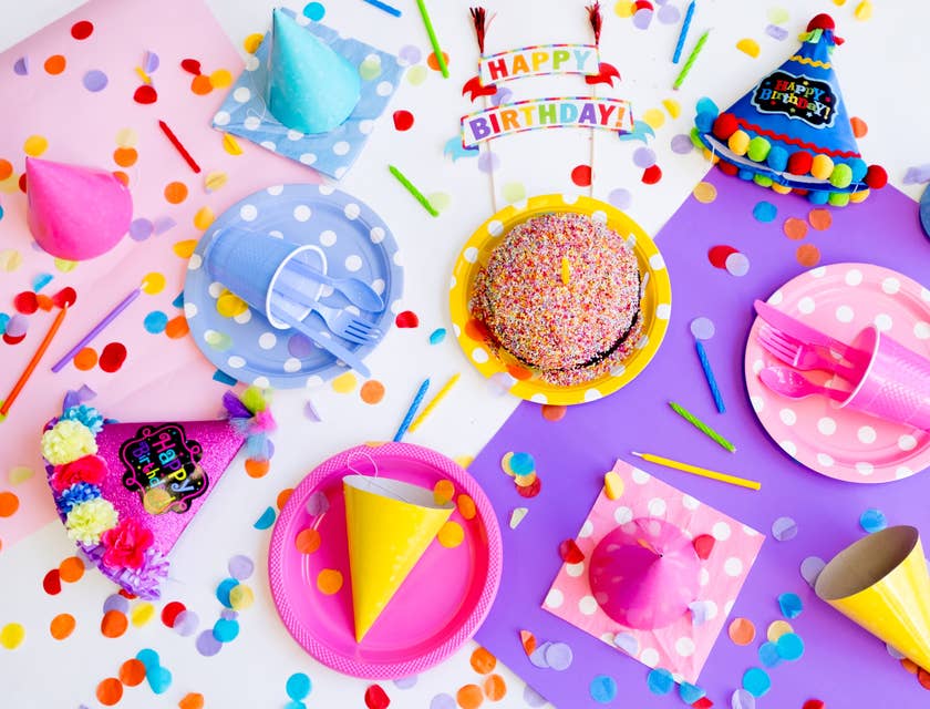 Gorros platos pastel velitas confeti cubiertos de plástico y un mantel en una casa de cumpleaños.