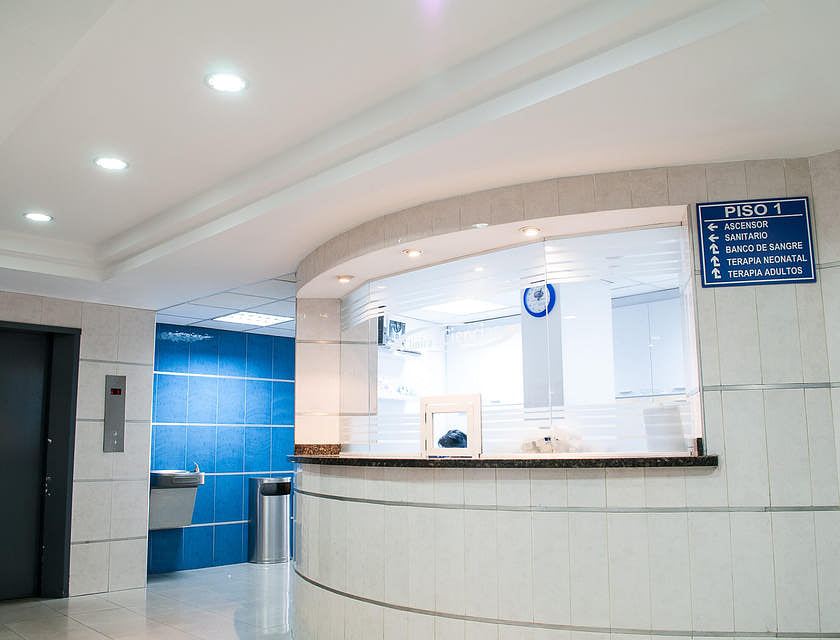 Interior de una clínica médica con vista a la recepción y el elevador.