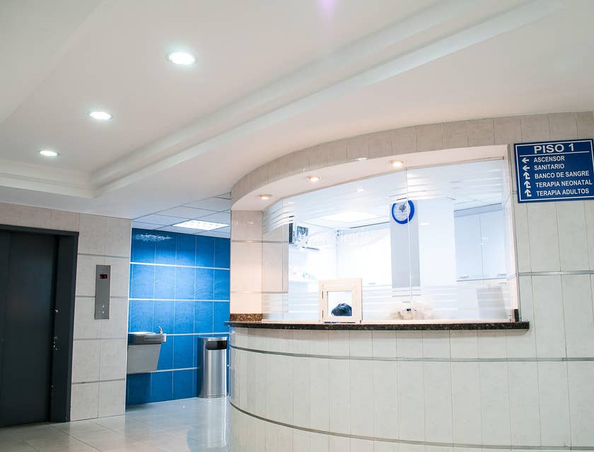 Interior de una clínica médica con vista a la recepción y el elevador.