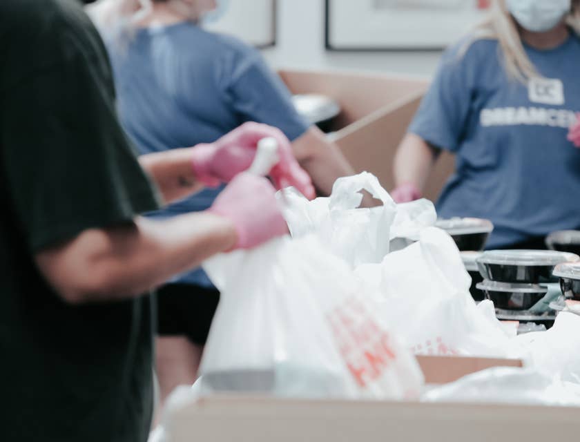 Personas organizando bolsas y charolas de alimentos en una institución de caridad.