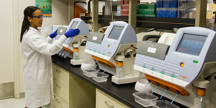 Laboratorista operando un equipo de análisis clínico en un laboratorio clínico.