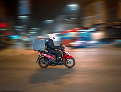 Persona en una moto trasladando un paquete en un negocio de mandados en moto.