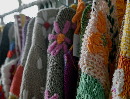Suéteres con motivos florales colgados en un negocio de accesorios de alpaca.