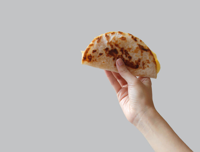 Una mano sosteniendo una baleada en un negocio de baleadas