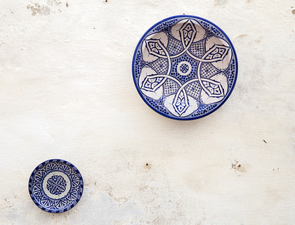 Dos platos de talavera colgados de una pared blanca descarapelada en un negocio de productos artesanales.