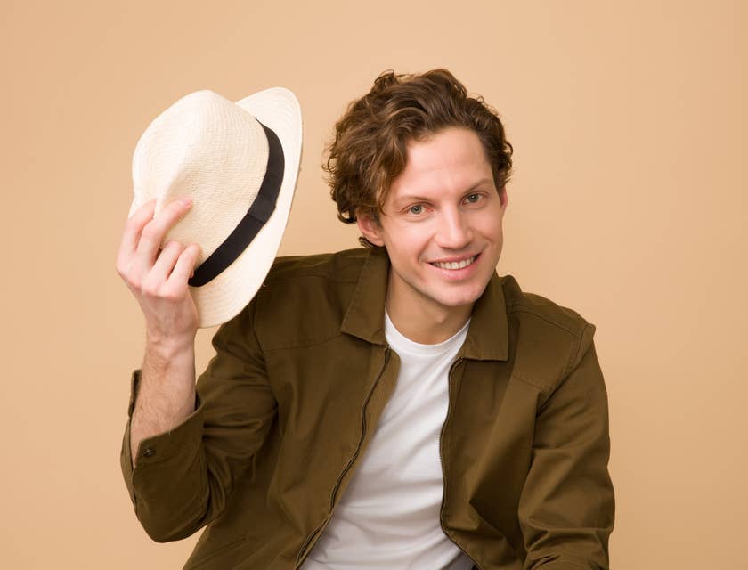Un hombre joven viendo de frente y sonriendo sosteniendo un sombrero de un negocio de sombreros de paja toquilla.