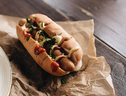 Un completo servido sobre una mesa de madera en un puesto de completos.