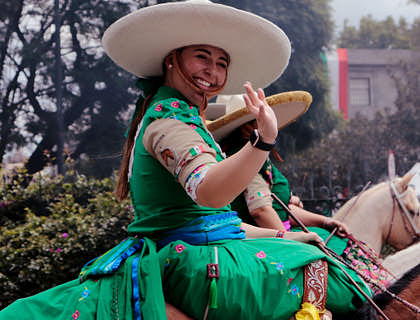 Una escaramuza montada en un caballo saludando con un traje de una tienda de trajes de charro y escaramuza.