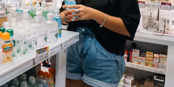 Una ragazza che indossa una mascherina mentre compra un sapone antibatterico in una parafarmacia.
