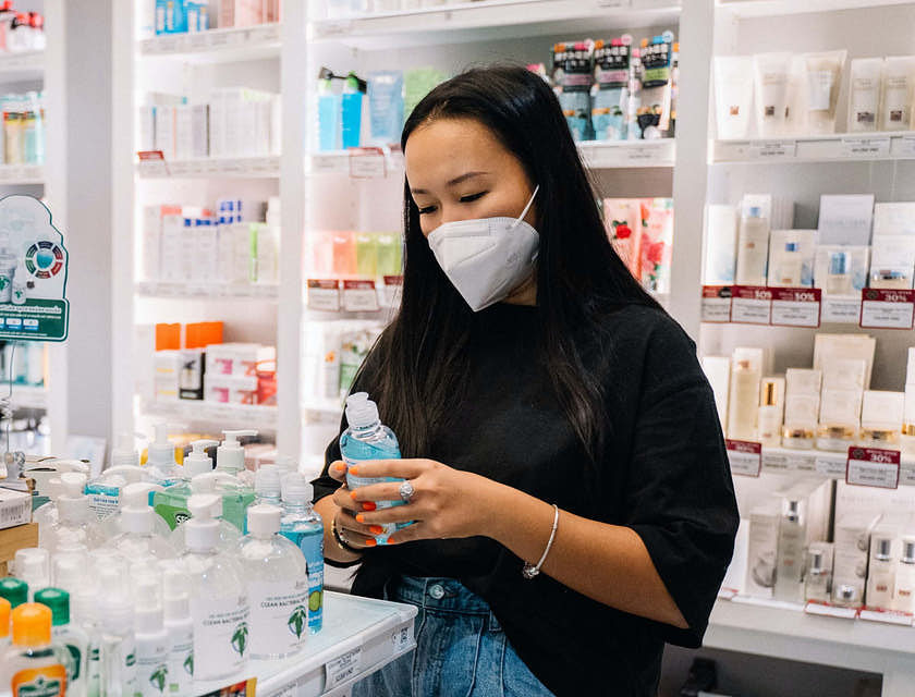 Una ragazza che indossa una mascherina mentre compra un sapone antibatterico in una parafarmacia.