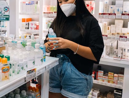 Una ragazza che indossa una mascherina mentre compra un sapone antibatterico in una parafarmacia.