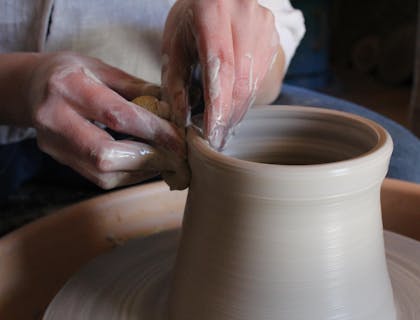 Un·e artisan·e train de faire un pot sur un tour de poterie.