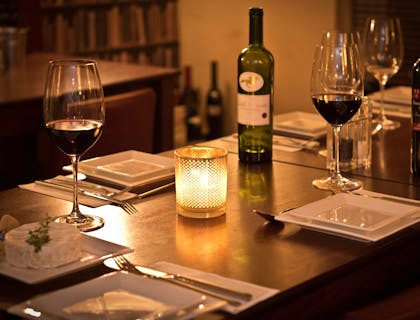 Table mise avec assiettes blanches carrées, verres de vin et camembert