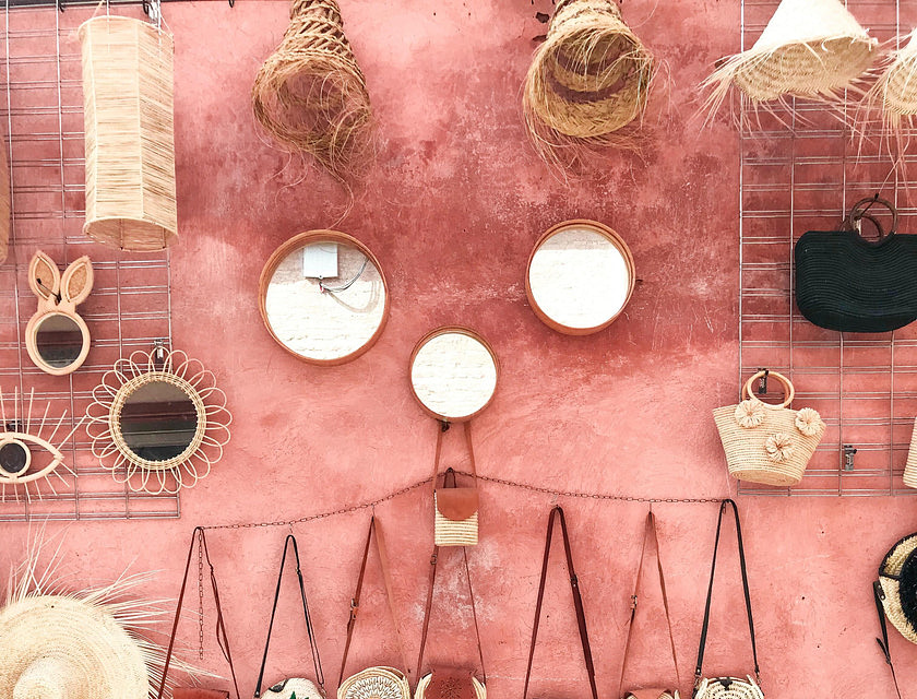 Paniers et chapeaux en osier contre un mur rose dans un boutique d'artisanat.