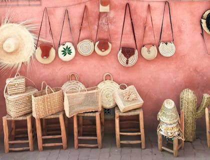 Paniers et chapeaux en osier contre un mur rose dans un boutique d'artisanat.