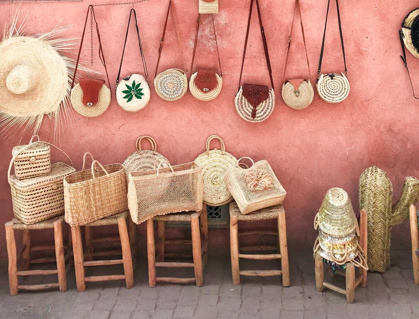 Paniers et chapeaux en osier contre un mur rose dans un boutique d'artisanat.