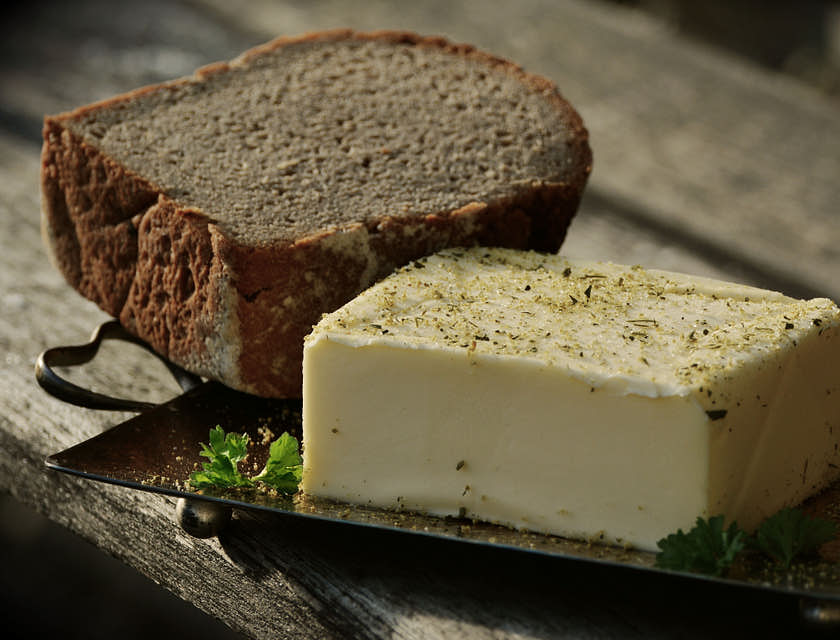 Un morceau de beurre et de pain dans un plat en métal sur une table.