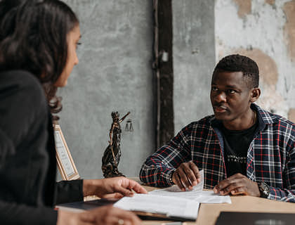 A young immigrant talking with his lawyer at an immigration law firm.