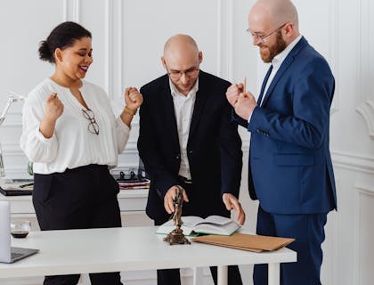 Abogados de un despacho de seguridad social parados alrededor de una mesa en su oficina.