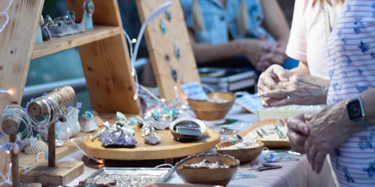 Two customers looking at merchandise being sold at a bazaar stand.