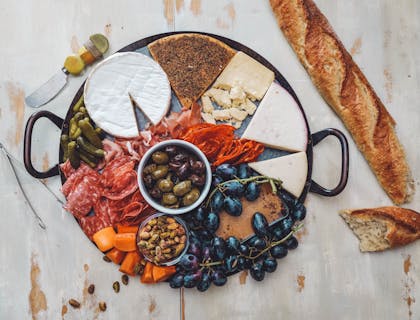 Plato con una gran variedad de quesos y comida suiza con una baguette al lado en un restaurante de comida suiza.