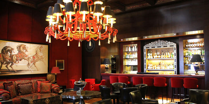 A lounge with red seats behind three tables, and red lighting.