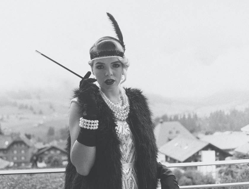 Imagen en blanco y negro de una mujer vestida de flapper sosteniendo un cigarrillo en un negocio estilo gángster de 1920