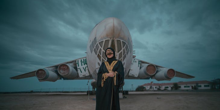 A woman in an abaya standing in front of an airplane.