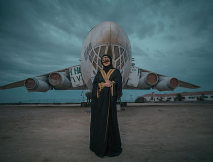 A woman in an abaya standing in front of an airplane.
