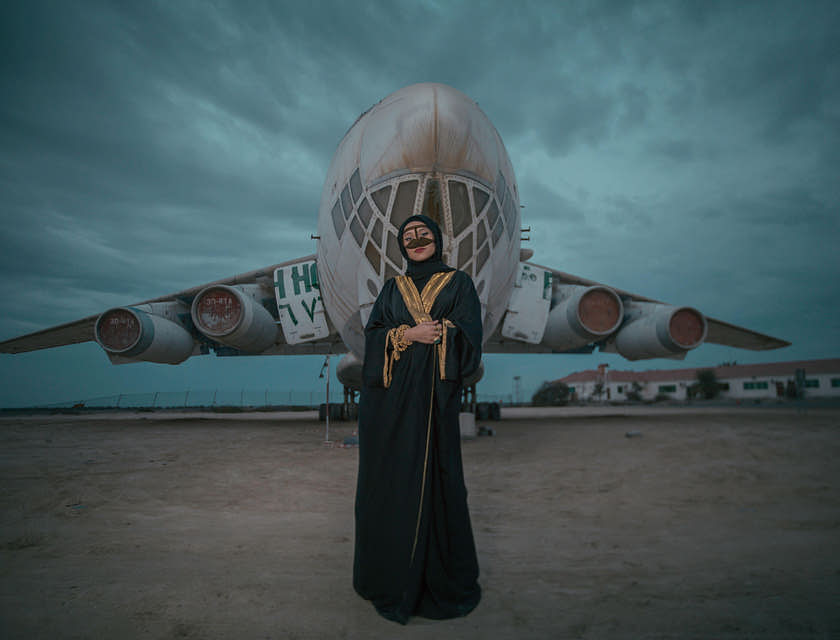 Une femme en abaya devant un avion.