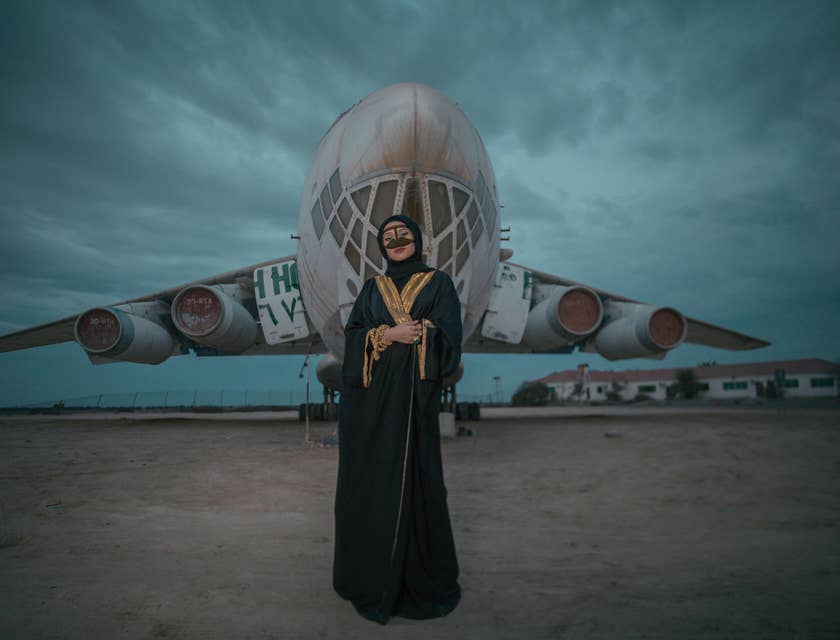 Une femme en abaya devant un avion.