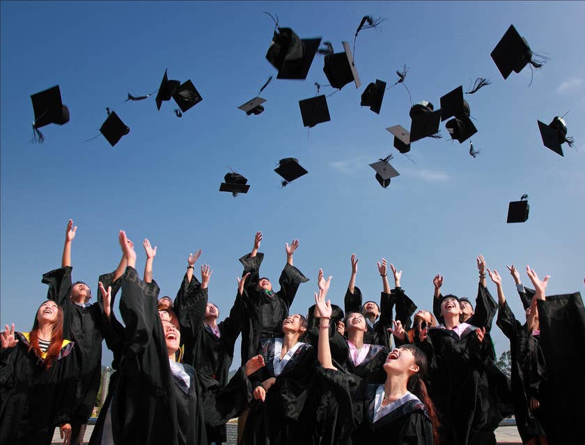 Degli studenti che lanciano il cappello in aria dopo essersi diplomati in un'accademia.