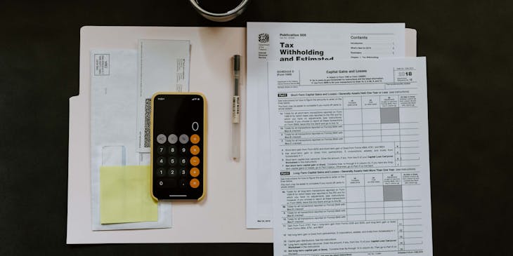 Tax accounting documents and a calculator in an open folder.