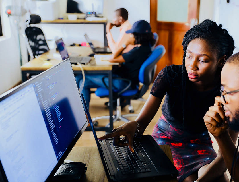 A woman providing adult education to a man using a laptop.