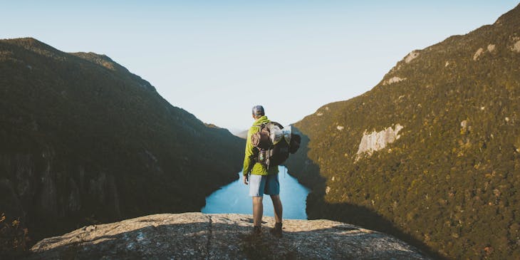 Hiker on an adventure tour standing on a boulder.