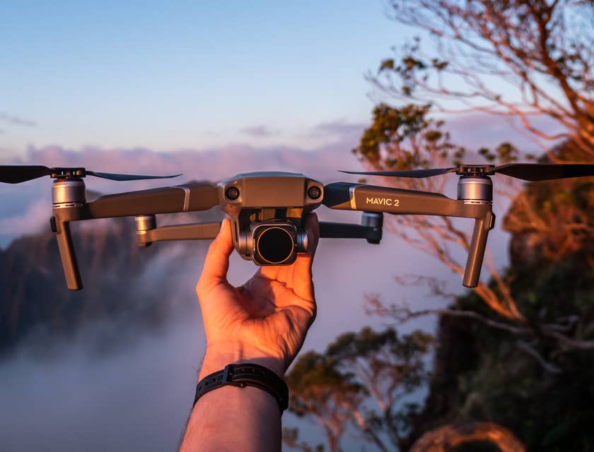 Ein Luftfotograf hält eine Drohne in der Hand, um Lauftaufnahmen im Gebirge zu machen.