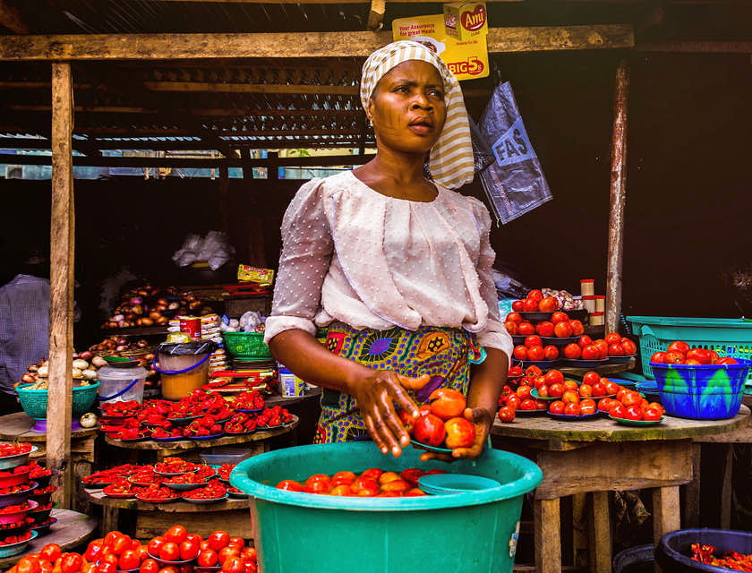 Una donna africana con in mano dei pomodori.