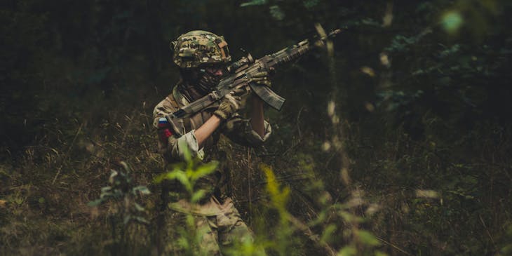 Homme dans des herbes hautes pendant une partie d'airsoft.
